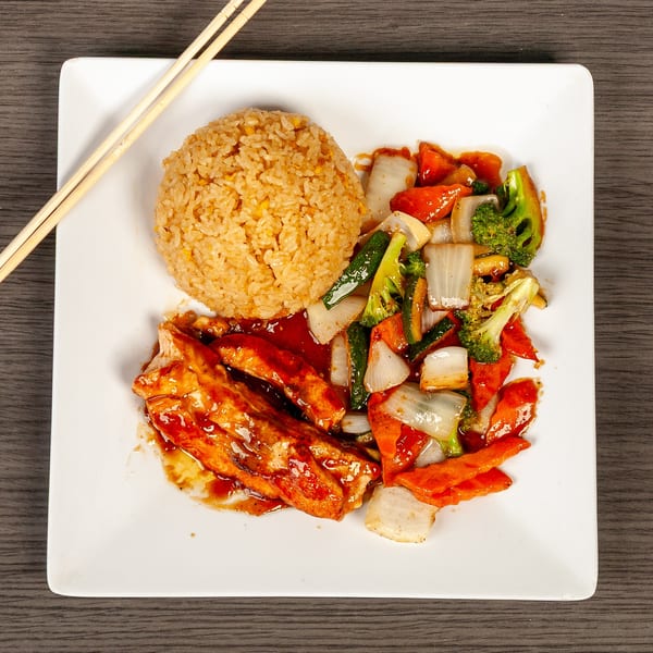 Teriyaki chicken with fried rice and stir-fried vegetables on a white plate with chopsticks.