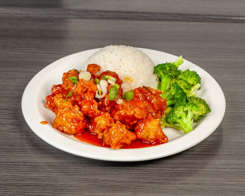 General Tso's chicken with white rice and steamed broccoli on a white plate.