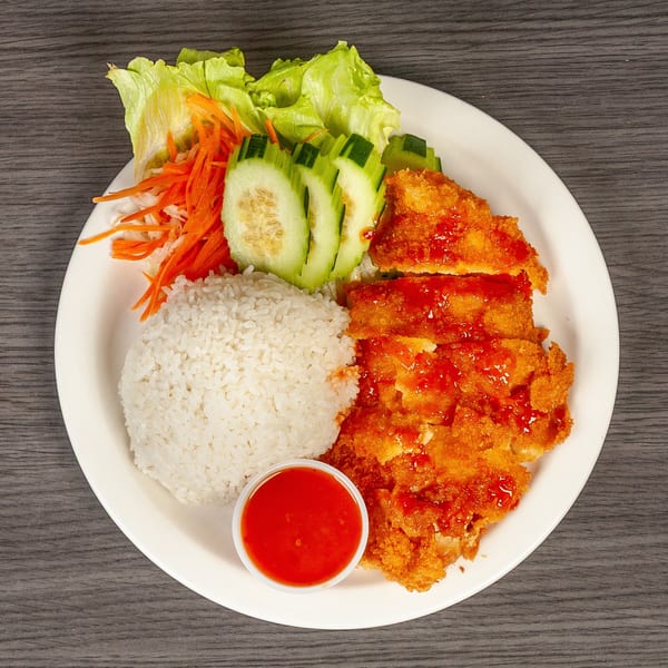 Crispy fried chicken with sweet chili sauce, white rice, lettuce, shredded carrots, and cucumber slices.