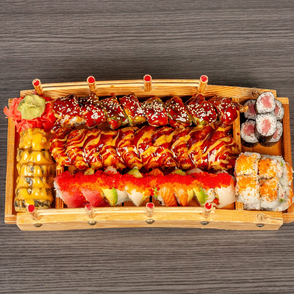 A large wooden boat filled with various sushi rolls, including tuna, salmon, and eel.
